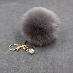 Detail of dark grey faux fur keychain with gold lobster clasp and sparkling crystal ball