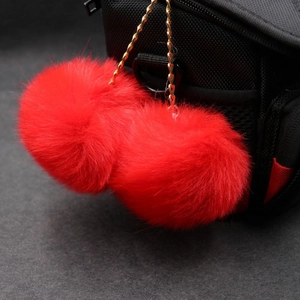 Detail of fluffy red faux rabbit fur double pompom keychain with golden metal chain