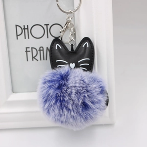 Detail of a cat plush keychain with a black faux leather head and purple gradient pompom