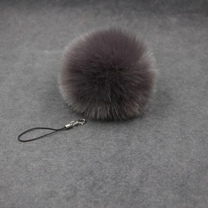 Detail of dark purple plush faux fur pompom with silver lobster clasp and black lanyard