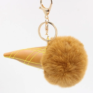 Close-up of fluffy fur pompom ice cream keychain with brown leather cone and gold hardware