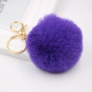 Close-up of a fluffy purple faux rabbit fur pompom keychain with golden metal lobster clasp