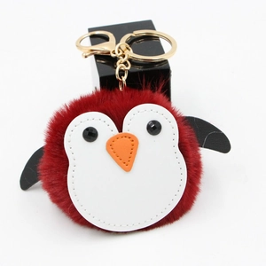 Détail d'un porte-clés pingouin en peluche bordeaux avec fermoir doré et chaîne