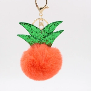 Detailed view of fluffy orange pineapple keychain with green sequins and gold metal hook