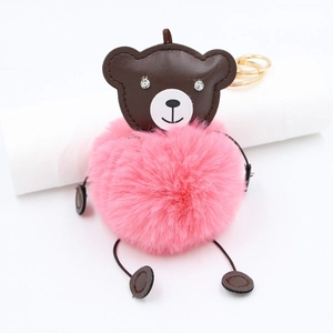 Detail of cute bear keychain with pink plush fur ball and brown leather head charm