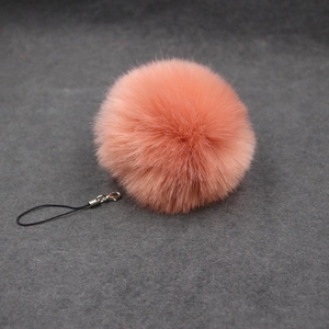 Close-up of coral pink faux fur ball keychain with black lanyard and metal lobster clasp