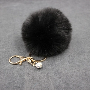 Detail of black faux fur pompom keychain with golden lobster clasp and rhinestone ball