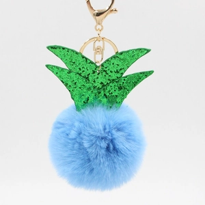 Close-up of light blue faux fur pineapple keychain with green sequins and gold hardware