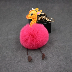 Macro view of cartoon giraffe plush pom pom keychain with pink fur and golden clasp