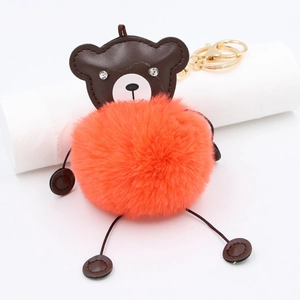 Close-up of brown PU bear head with rhinestone eyes and bright orange plush fur pompom