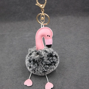 Détail du porte-clés flamant rose en cuir avec pompon noir et blanc et fermoir doré chic