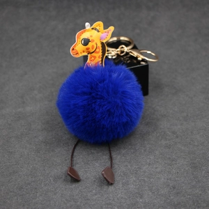 Detail of creative giraffe plush pom-pom keychain with blue fur and golden ring