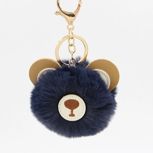 Detail of blue plush bear keychain with golden metal clasp and fluffy faux fur texture