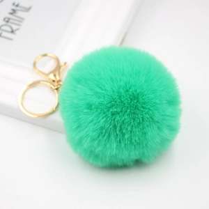 Detail of soft mint green faux fur pompom keychain with polished gold lobster clasp