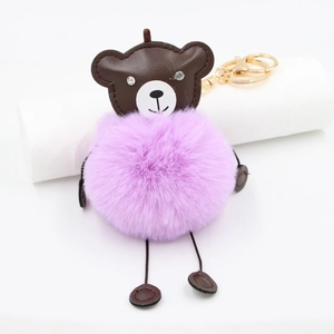 Close-up of a brown leather bear keychain with fluffy purple faux fur ball and gold clasp