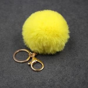 Gros plan d'un porte-clés pompon en fausse fourrure jaune 8cm avec fermoir doré