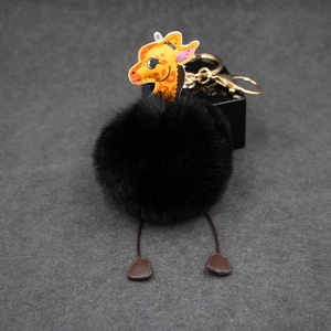 Detailed close-up of fluffy black faux fur giraffe keychain with golden metal clasp