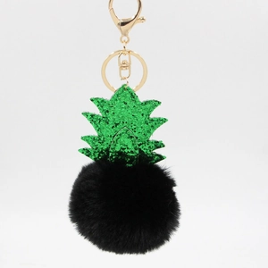 Detailed shot of pineapple keychain with green sequins and black plush faux fur pom-pom