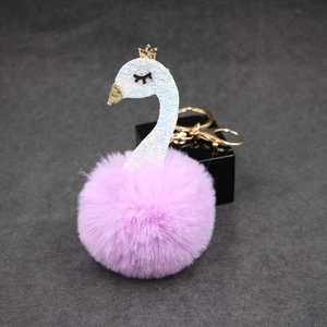 Detailed close-up of a plush swan keychain with pink pompom and golden sequins