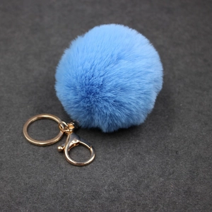 Détail d'un porte-clés pompon en fausse fourrure bleu clair avec fermoir doré poli