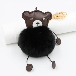 Detail of plush black fur ball and brown leather bear keychain with golden clasp
