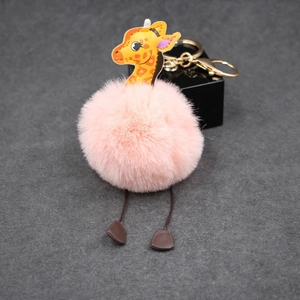 Detailed view of a pink plush pompom giraffe keychain with golden metal alloy clip accessory