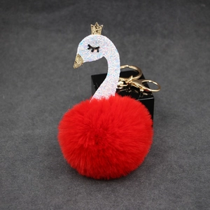 Close-up of red fluffy swan keychain with gold crown and sparkling sequin details