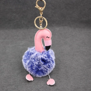 Vue détaillée du pompon violet et du porte-clés flamant rose doré avec attache en or