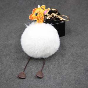 Detailed macro view of a fluffy white giraffe pompom keychain with golden metal clasp