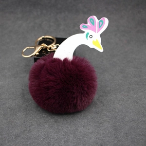 Vue détaillée du porte-clés pompon paon en fausse fourrure violette et fermoir doré