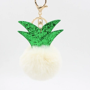 Close-up of white plush pineapple keychain with green glitter leaves and gold clasp