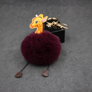 Detail of burgundy plush giraffe keychain with a golden ring on dark surface
