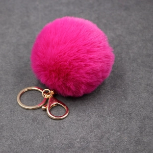 Détail du porte-clés pompon en fausse fourrure rose rouge avec anneau en métal doré