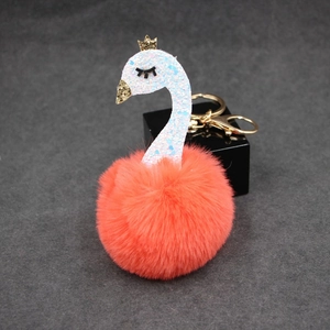 Detail of creative swan plush keychain featuring orange fur pompom and golden crown
