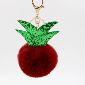 Detail view of small pineapple keychain with green glitter leaves and red plush pom-pom charm