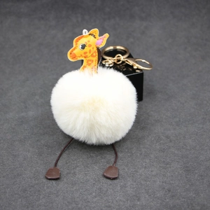 Detail of giraffe plush ball keychain with golden metal clasp and faux fur on grey base