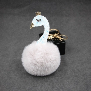 Fluffy swan keychain with gray fur pompom, blue sequined neck and golden crown