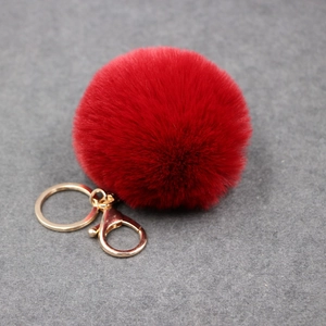 Détail du pompon en fausse fourrure rouge avec fermoir mousqueton doré et anneau porte-clés