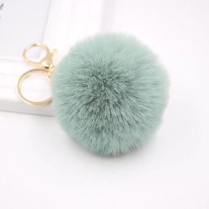 Detail of soft mint green faux fur pompom keychain with shiny gold lobster clasp