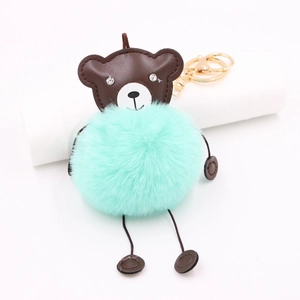 Detail of mint green faux fur bear keychain with brown leather head and golden metal clasp
