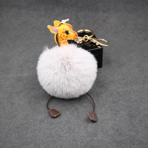 Detail of giraffe plush ball keychain with golden metal clasp on grey felt background