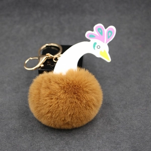 Détail d'un porte-clés paon en peluche avec boule de fourrure marron et anneau doré
