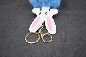 Detail of blue faux fur pom-pom rabbit keychain with white ears and gold metal clasp