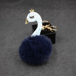 Detail of creative blue swan fur ball keychain with gold crown and sequin neck fabric