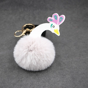 Gros plan d'un porte-clés pompon en forme de cygne avec anneau en métal doré brillant