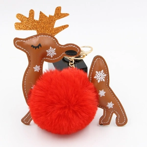 Close-up of a Christmas reindeer plush ball keychain with golden antlers and red faux fur
