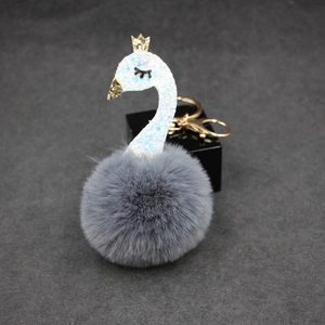 Detail of gray plush swan keychain with blue sequins, gold crown and metal clasp
