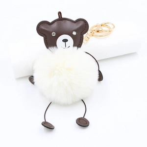 Close-up of cute brown bear plush keychain with white faux fur pompom and golden clasp