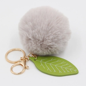 Detail of faux fur pom pom fruit keychain with leaf pendant and golden metal clip