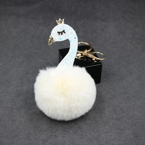 Detailed view of light blue glitter swan pendant with soft beige pompom and gold keychain